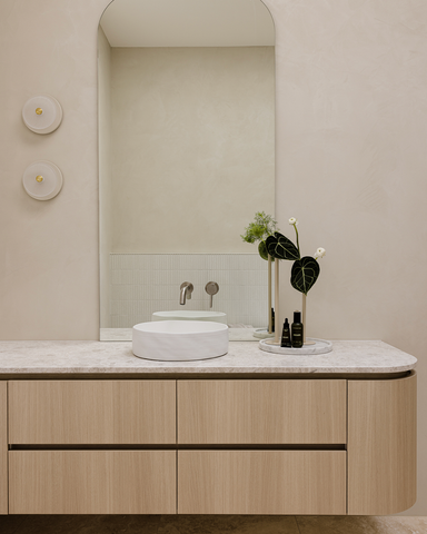 A perspective of the ensuite bathroom's walk-in wardrobe with curved timber joinery, offering a seamless transition into the luxurious bathroom space. The design elements complement each other to create a cohesive and stylish environment.