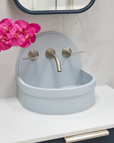 A stylish powder blue Betty basin elegantly mounted on a curved blue vanity, creating a harmonious and visually pleasing bathroom ensemble.