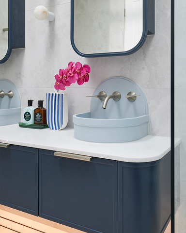 A chic powder blue Betty basin gracing a gracefully curved blue vanity, enhancing the aesthetics of the bathroom with its sophisticated design.