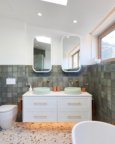 The Mint Funl basin beautifully contrasts with a white vanity, complementing the vibrant green tiles and terrazzo floor tiles, creating a fresh and contemporary bathroom design.