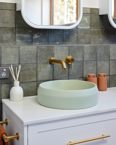 A close-up view of the striking Mint Funl basin, a focal point in this bathroom with its vibrant green tiles and terrazzo floor tiles, exuding modern sophistication.