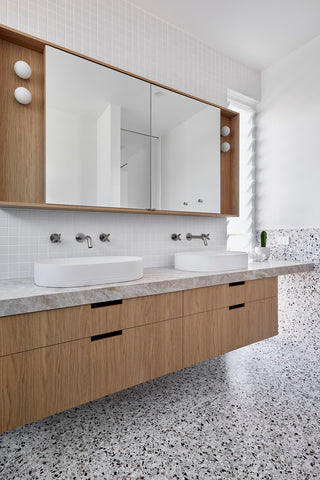 His-and-hers Ivory Nood Co Pill basins set against a backdrop of terrazzo tiles in the luxurious primary ensuite.