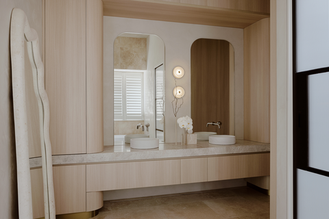 An overall view of the spacious ensuite bathroom, highlighting the harmonious combination of design elements, including the Zenn Design bed, window seat, Soktas hand-blown lighting, fluted glass and steel doors, and the Slip basins by Nood Co in Ivory. The bathroom exudes an atmosphere of opulence and tranquility, making it a true retreat.