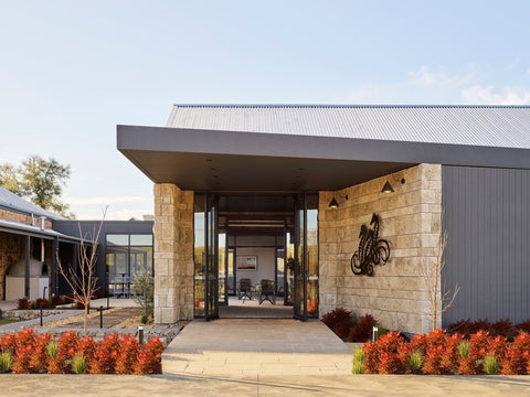 Approaching the front of Taylors Wines, you're greeted by a picturesque scene. The winery's facade features a blend of contemporary architecture and historic charm, with inviting pathways leading to the entrance. Lush landscaping and well-maintained gardens frame the building, creating a harmonious atmosphere that embodies the essence of Clare Valley wine country.