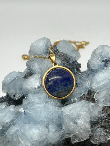 A gold necklace with a lapis lazuli stone pendant, the blue stone featuring gold flecks and veining