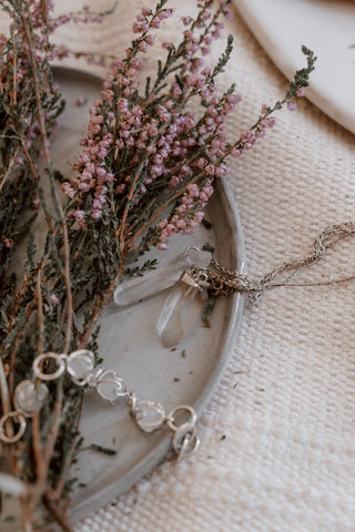 Une collection de colliers à pointes de cristal suspendus à des crochets, chaque collier présentant un cristal unique de différentes tailles et couleurs.