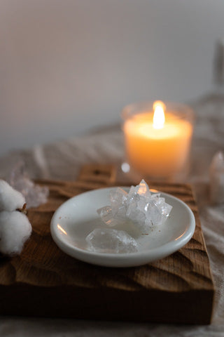 Close-up of a white raw crystal with a lit candle in the background, casting a warm glow on its textured surface.