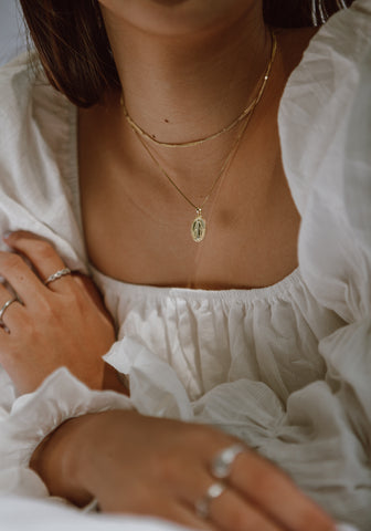 layered gold necklaces with a delicate chain and small pendant, resting on bare skin