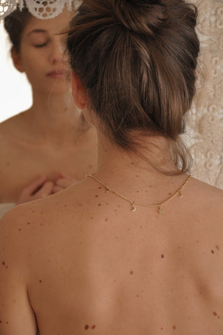 A gold necklace with a delicate chain and small pendant, resting on bare skin