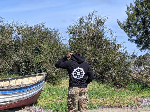 Cali8Fold Hoodie, black hoodie, Buddhist wheel on back of hoodie, man standing next to boat
