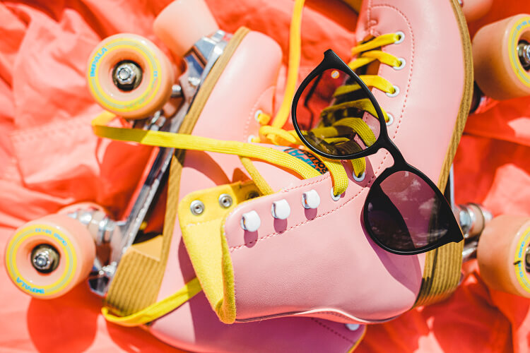 black sunglasses sitting on pink roller skates in the sun