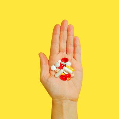 hand holding vitamins with yellow background