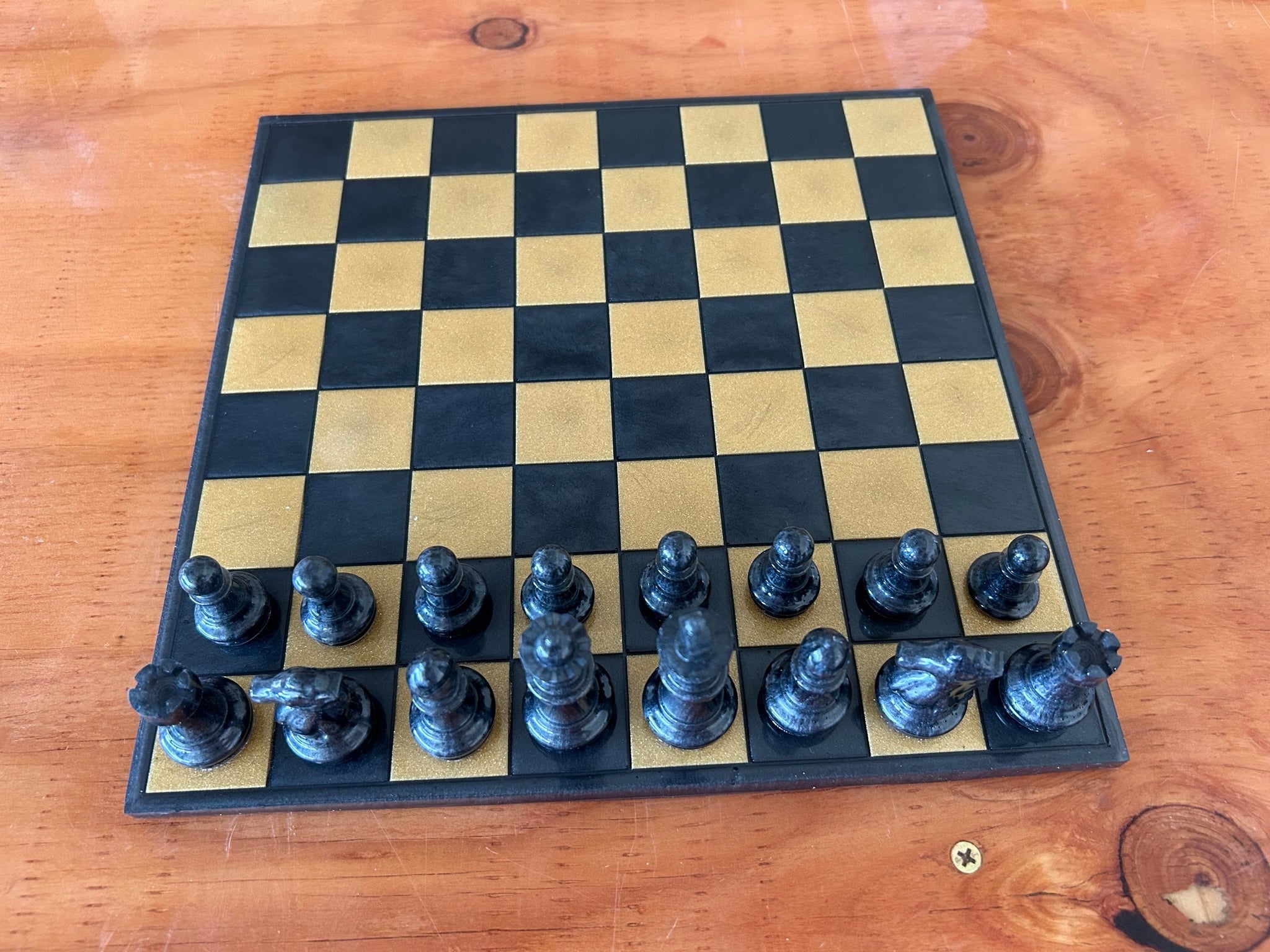 Gold and black chessboard made of epoxy resin and pigments with black pieces.