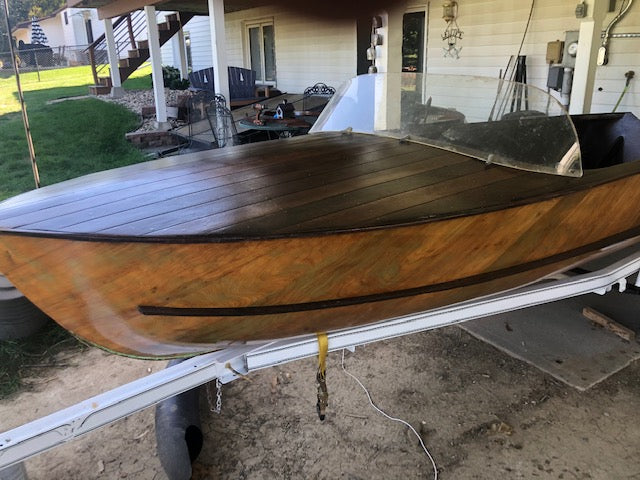 Dark colored wood Dundee boat on trailer. Boat is redone with lightweight fiberglass and epoxy resin.