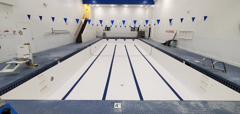 Large indoor olympic size pool newly resurfaced with white gel coat and dark blue painted lines.