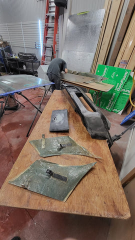 Man leaning over table working on fiberglass pieces for corvette custom build.