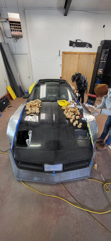 Corvette being customized in garage surrounded by tools.