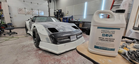 Corvette being customized in background with Fiberglass Warehouse gallon of ortho laminating resin in the front on a table.