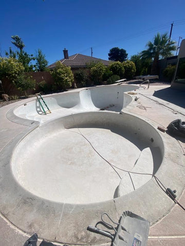 Round hot tub connected to empty swimming pool ready to be resurfaced.