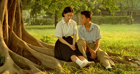 A boy and girl sit beneath a tree in "A Brighter Summer Day"