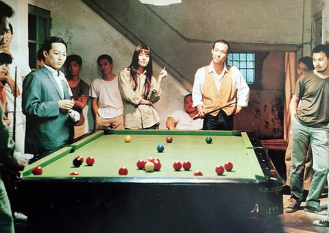 A group of young adults stand around a brightly lit pool table