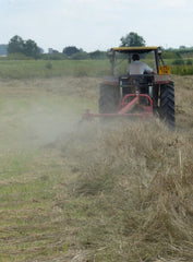 Small tractor turning hay