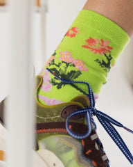 a lime coloured sock with bright embroidered flowers on a person wearing a vintage running shoe 