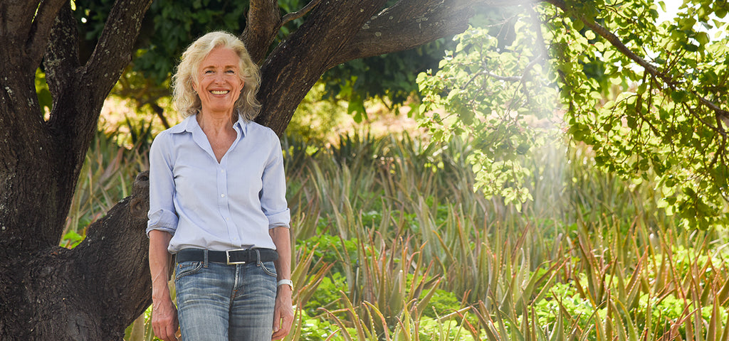 Santaverde founder Sabine Beer in the midst of her own aloe vera fields, leaning against a tree