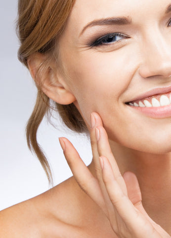 Woman strokes her cheek with her fingertips.    