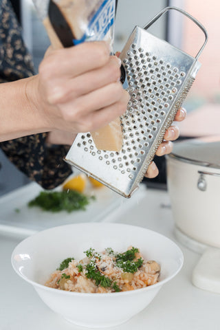 Grating Grana Padano on freshly cooked seafood risotto.