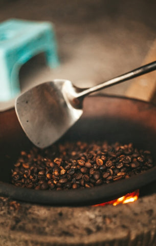 Robusta coffee beans being roasted over high heat in a wok. Photo by Kseniia Ilinykh.