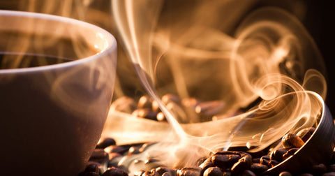 Closeup photo a brown mug full of steaming coffee surrounded by coffee beans