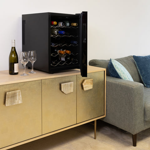 Photo of Koolatron's 20 bottle single zone wine cooler on a gold-colored sideboard beside a gray sofa