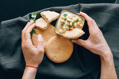 a person holding bread with hummus