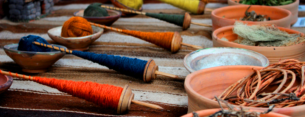 Spindles with alpaca wool in different colours and the plants used for dyeing