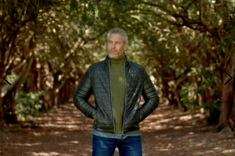 Man stood in the woods wearing a green turtleneck under the Olive Roman Puffer Leather Jacket