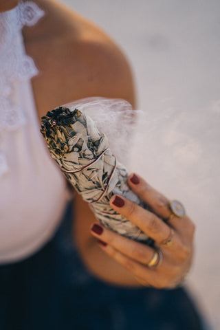 Woman smudging some sage as part of a self care ceremony. 