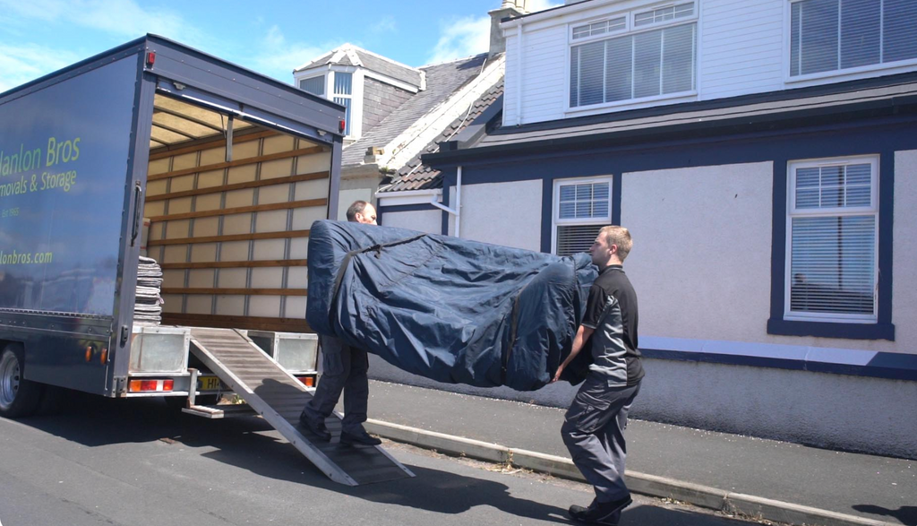 The Hanlon Bros removals team loading a couch into a moving van.