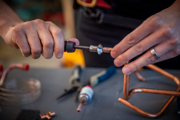 A woman connects two copper heat pump parts