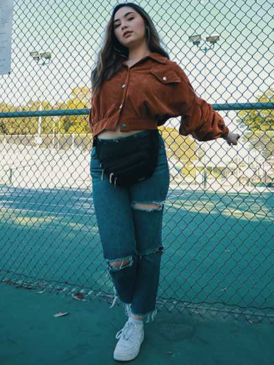 women-tan-leather-jacket-with-ripped-blue-jeans-and-white-sneakers