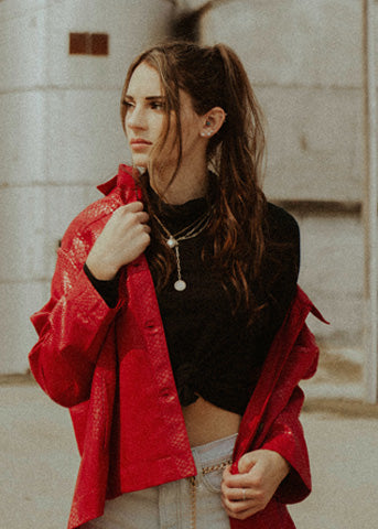 women-in-red-leather-jacket-with-black-cropped-top-and-white-jeans-with-beatufil-locket-set