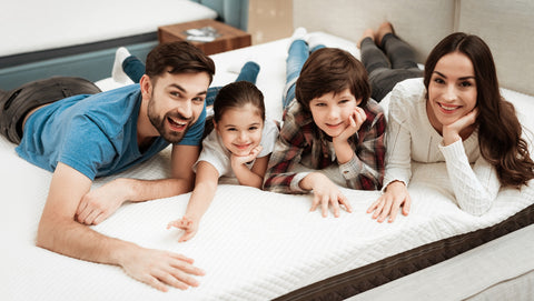 family of four laying on a mattress in a store, trying it out