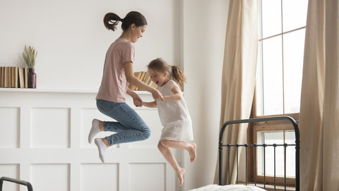 woman and girl playing, jumping on a bed