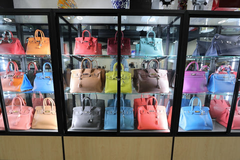 A wall of Hermès Birkin bags sits inside a display case.