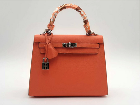 An orange Hermès Birkin bag is on display.