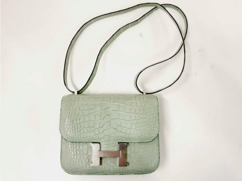 A light green Constance bag is on display.