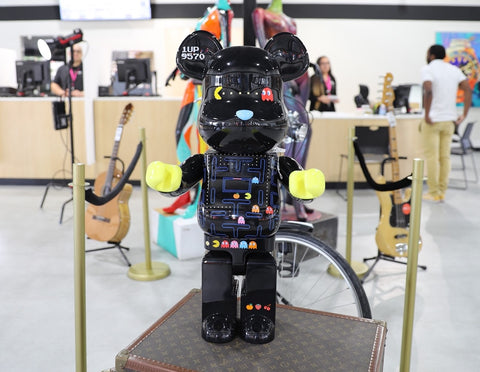 A black Pacman Bearbrick is standing Louis Vuitton suitcases.