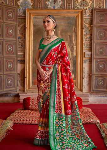 woman side pose in red patola saree with green blouse