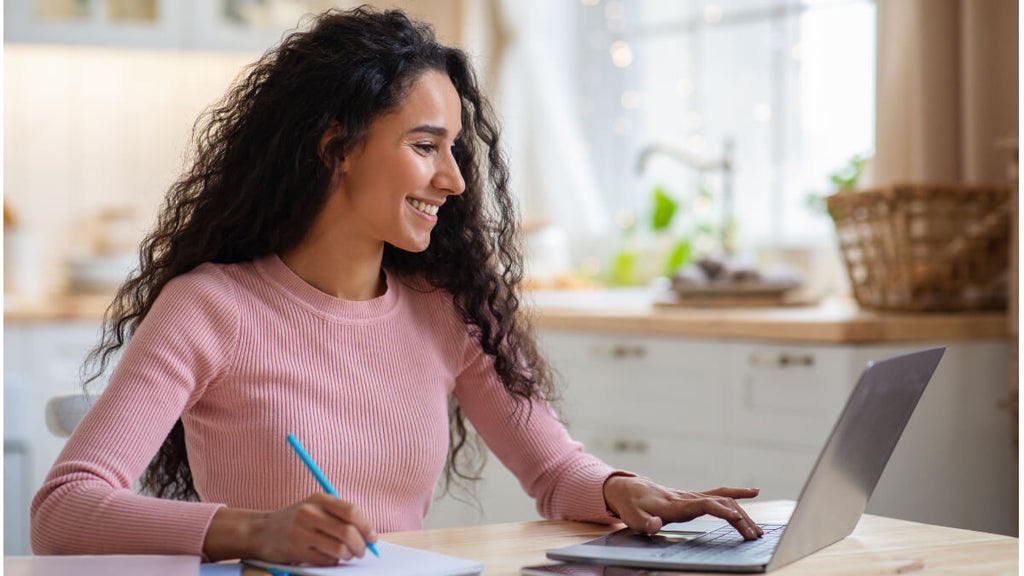 woman in front of laptop in kitchen working on alternative certification educator prep program