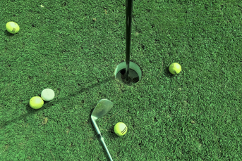 Rubber core golf balls and a club on the green near the pin